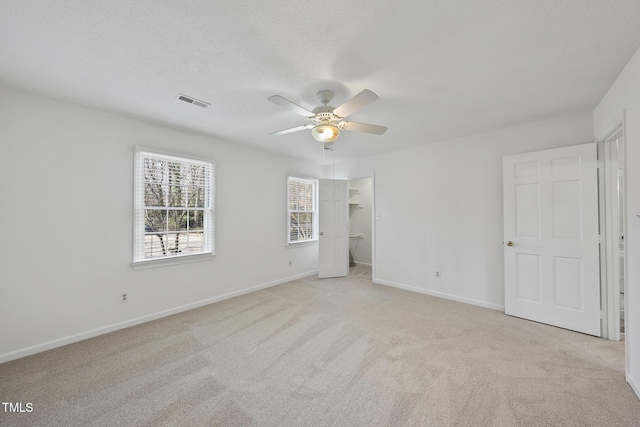 unfurnished bedroom featuring a textured ceiling, baseboards, and light colored carpet