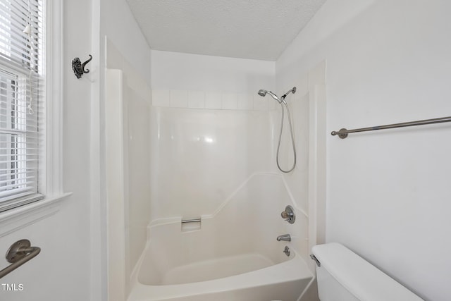 bathroom with toilet, a textured ceiling, and shower / bathing tub combination