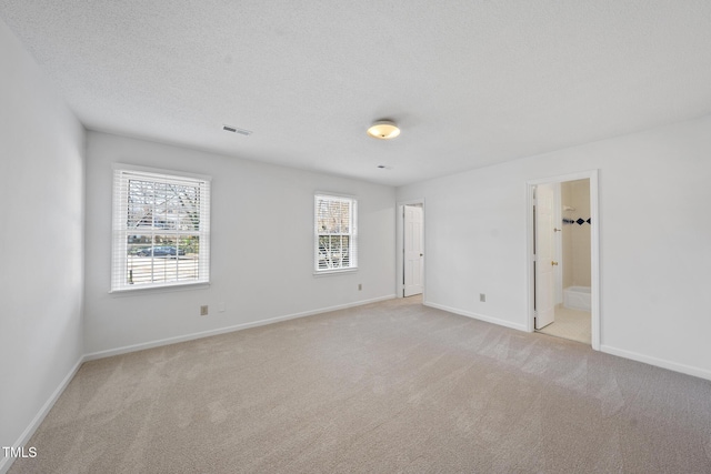 unfurnished bedroom featuring baseboards, visible vents, a textured ceiling, and light colored carpet