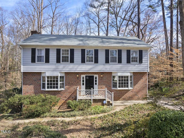 colonial home with a chimney and brick siding