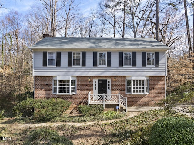 colonial-style house with brick siding and a chimney