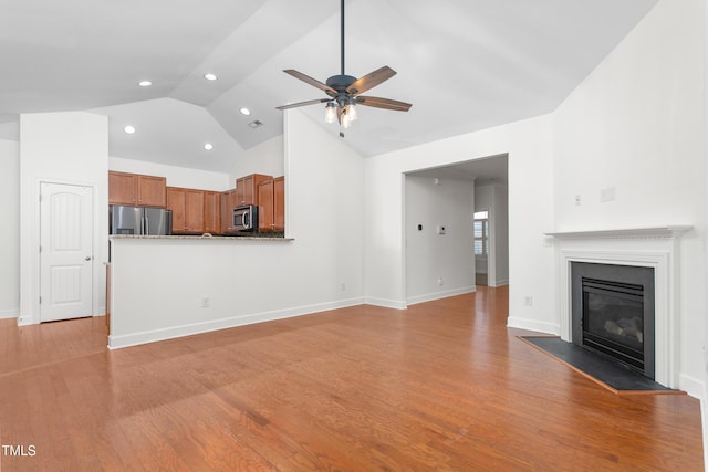 unfurnished living room with light hardwood / wood-style flooring, ceiling fan, and vaulted ceiling