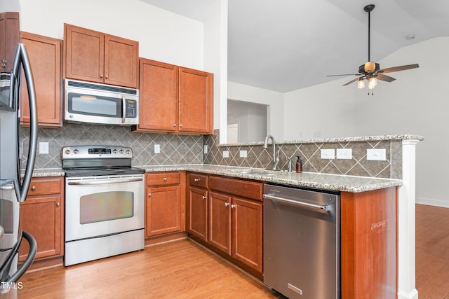 kitchen with light stone counters, light wood-type flooring, lofted ceiling, and appliances with stainless steel finishes