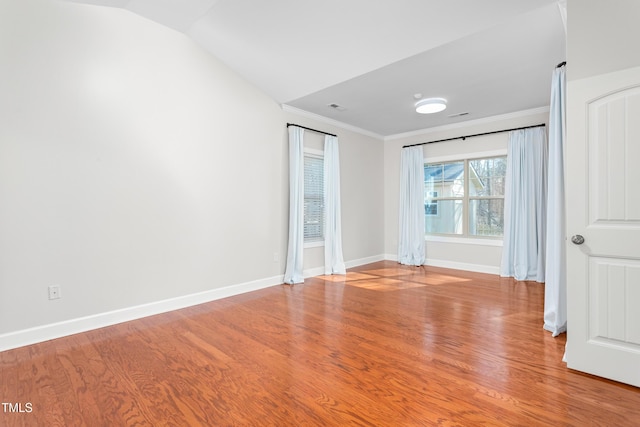 spare room featuring crown molding, lofted ceiling, and light hardwood / wood-style flooring