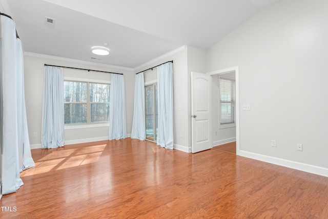 spare room featuring lofted ceiling, plenty of natural light, ornamental molding, and light wood-type flooring