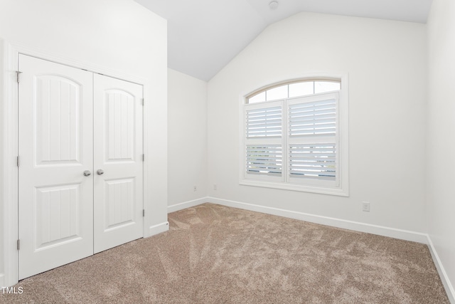 unfurnished bedroom featuring vaulted ceiling, a closet, and carpet flooring