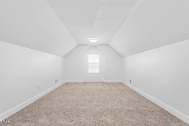 additional living space with lofted ceiling and light carpet