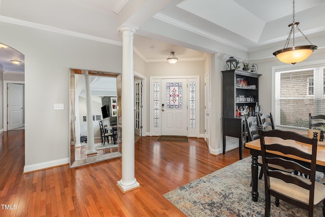 foyer entrance with hardwood / wood-style floors, ornamental molding, a raised ceiling, and ornate columns