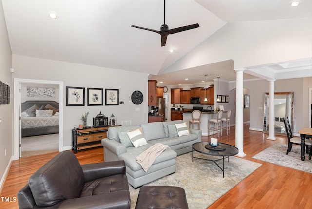 living room with ornate columns, high vaulted ceiling, sink, ceiling fan, and light wood-type flooring