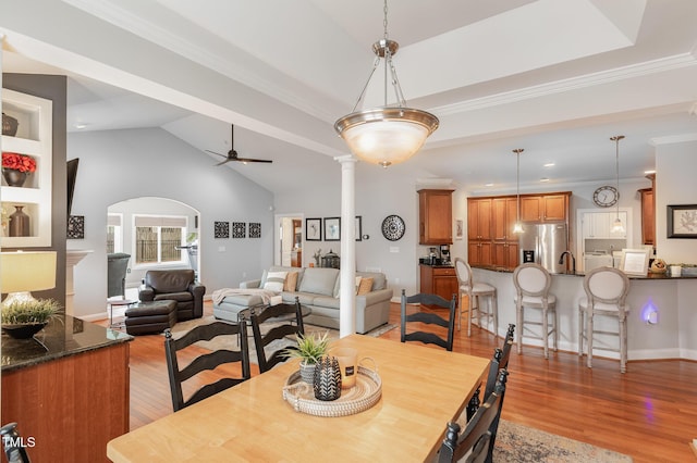 dining area featuring crown molding, ceiling fan, decorative columns, and light wood-type flooring