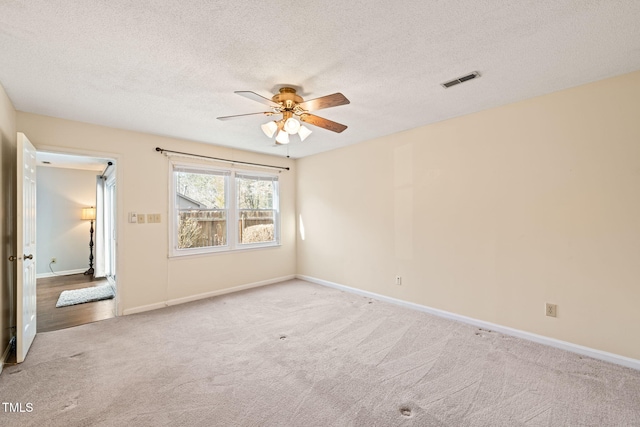 carpeted empty room featuring ceiling fan and a textured ceiling