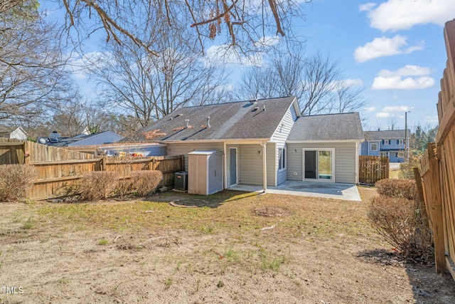 rear view of property with cooling unit, a yard, and a patio