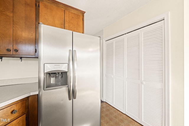 kitchen with stainless steel fridge with ice dispenser and a textured ceiling