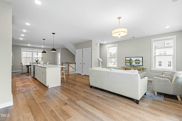 living room with plenty of natural light, sink, and light wood-type flooring