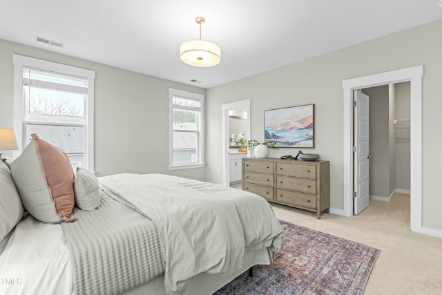 carpeted bedroom with a spacious closet and ensuite bath