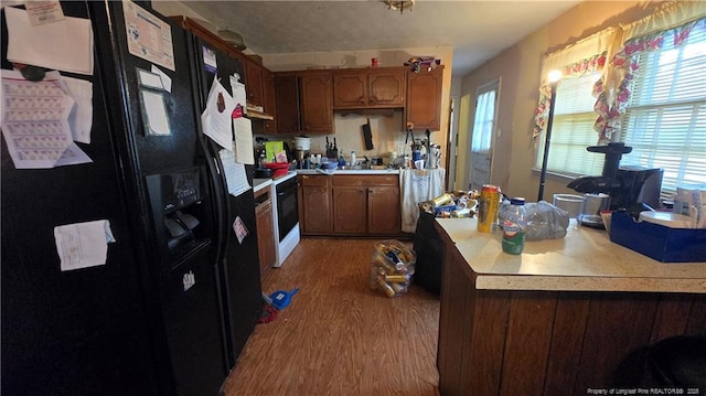 kitchen with range with electric stovetop, wood-type flooring, and black fridge