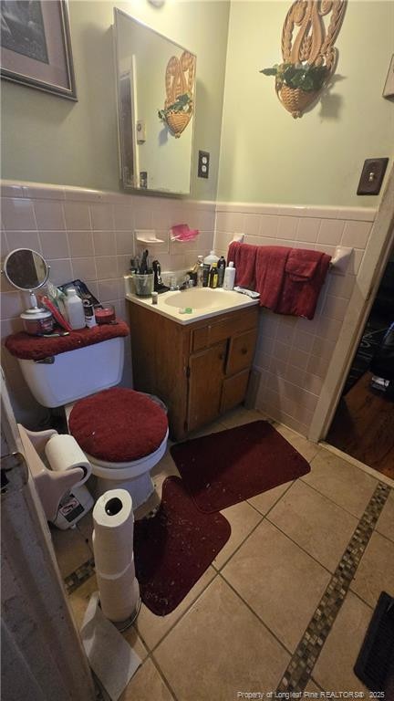 bathroom featuring tile patterned flooring, vanity, toilet, and tile walls