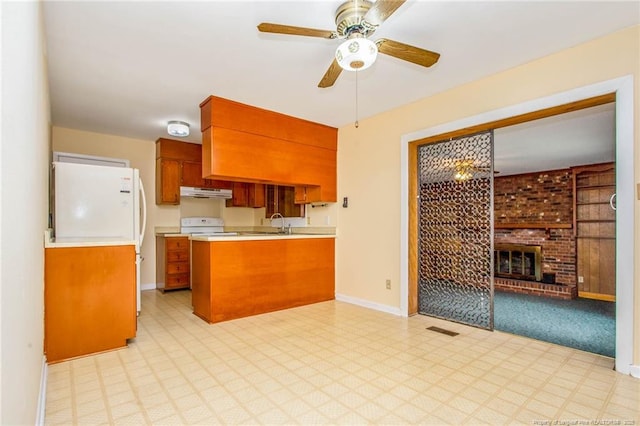 kitchen featuring sink, a brick fireplace, kitchen peninsula, ceiling fan, and white range with electric stovetop