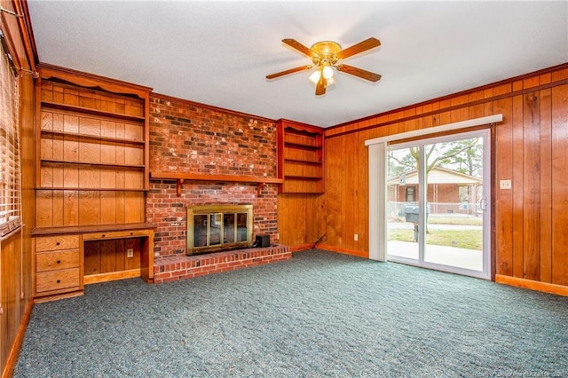 unfurnished living room with carpet flooring, a fireplace, and wooden walls