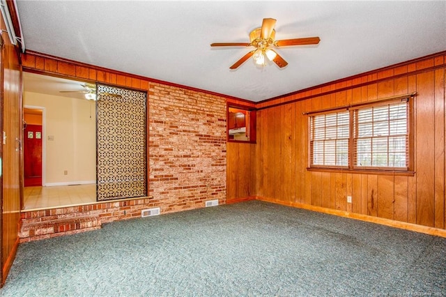 carpeted spare room featuring ceiling fan, brick wall, and wood walls