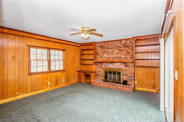 unfurnished living room with carpet, wooden walls, a textured ceiling, and a fireplace