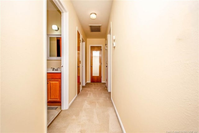 corridor with light carpet and sink