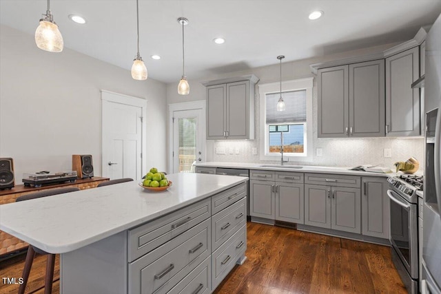 kitchen with a kitchen island, stainless steel gas range oven, pendant lighting, and gray cabinetry