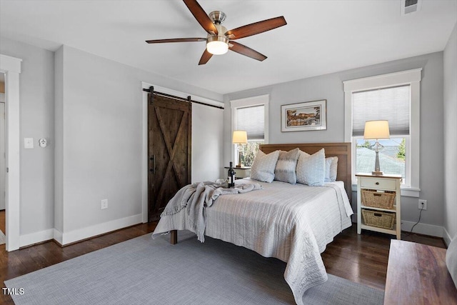 bedroom featuring dark hardwood / wood-style floors, a barn door, and ceiling fan