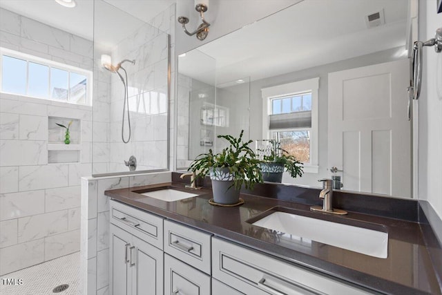 bathroom featuring a tile shower, vanity, and a healthy amount of sunlight