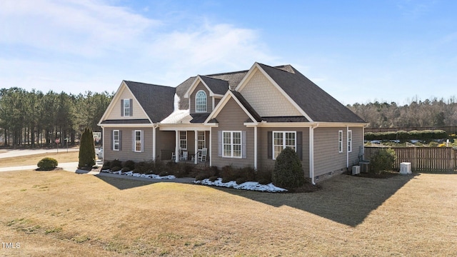 view of front facade with a front yard, central AC, and fence