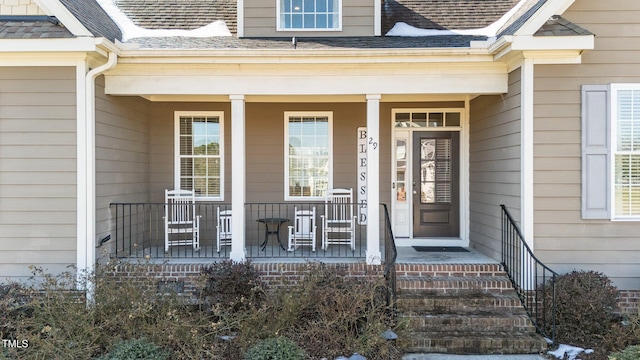 property entrance with a porch and roof with shingles