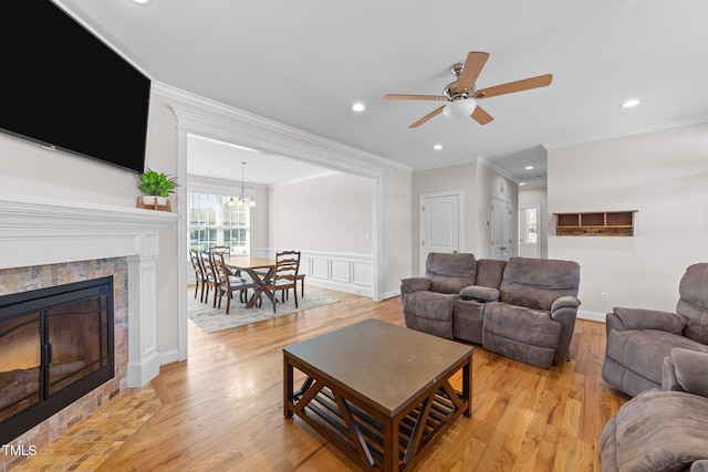 living area with a wainscoted wall, crown molding, a fireplace, recessed lighting, and light wood-style floors