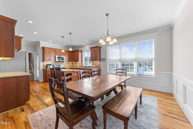 dining room featuring a notable chandelier, light wood-type flooring, and crown molding