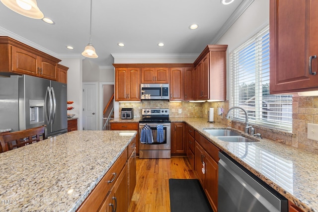 kitchen with light stone counters, stainless steel appliances, a sink, ornamental molding, and light wood-type flooring