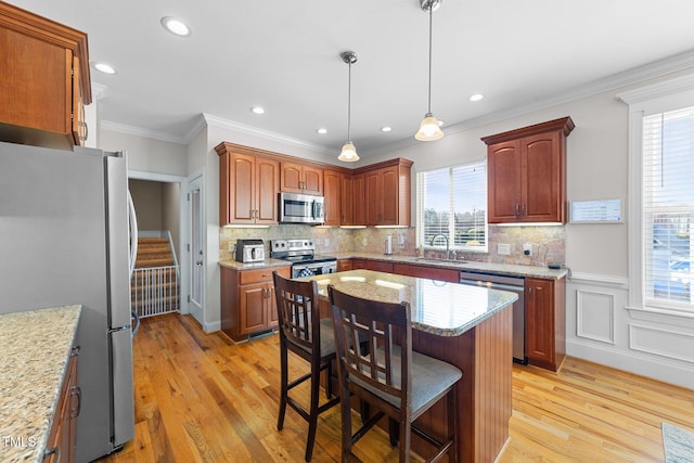 kitchen with appliances with stainless steel finishes, a breakfast bar, a sink, and light wood finished floors