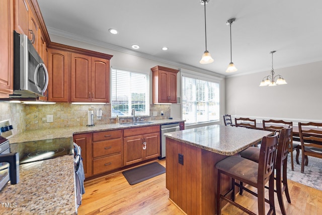 kitchen featuring light wood finished floors, appliances with stainless steel finishes, a sink, and ornamental molding