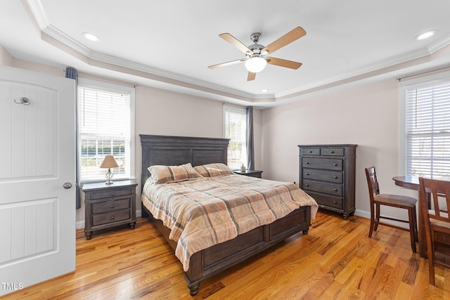 bedroom with light wood-type flooring, a raised ceiling, and crown molding