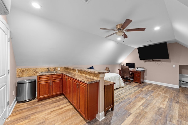 bedroom featuring a sink, light wood-type flooring, vaulted ceiling, and an AC wall unit