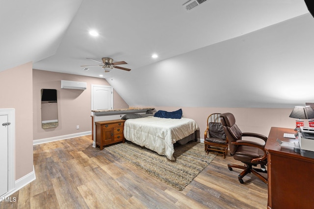 bedroom featuring vaulted ceiling, light wood-style flooring, a wall mounted air conditioner, and visible vents