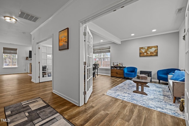 living area featuring crown molding, wood-type flooring, beamed ceiling, and a healthy amount of sunlight