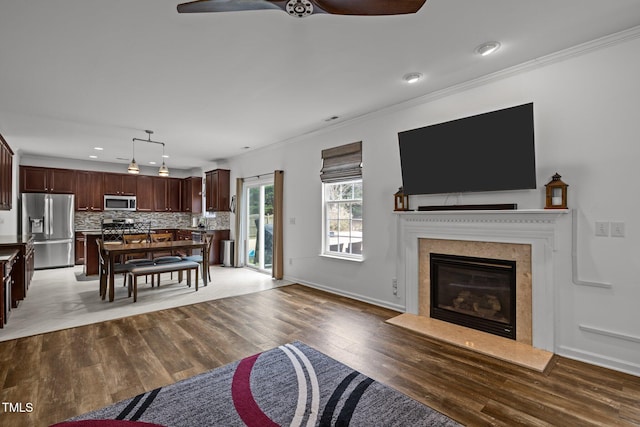 living room featuring ceiling fan, ornamental molding, dark hardwood / wood-style floors, and a premium fireplace