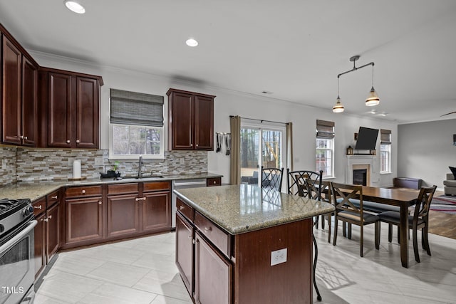 kitchen featuring sink, hanging light fixtures, a kitchen island, stainless steel appliances, and light stone countertops