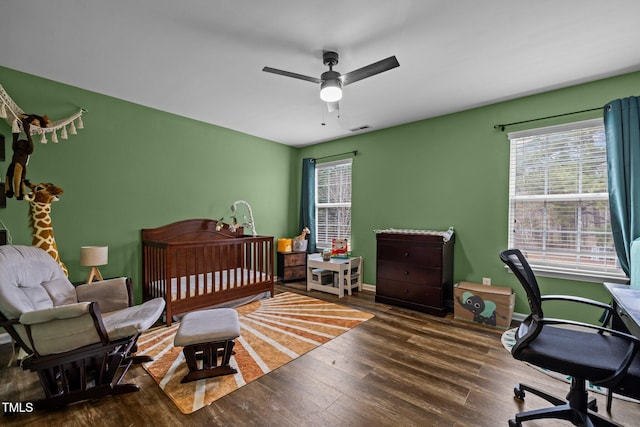 bedroom featuring multiple windows, dark hardwood / wood-style floors, and ceiling fan