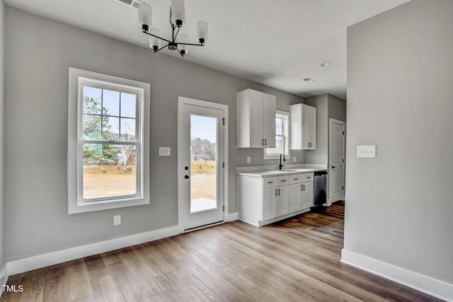 kitchen with sink, dishwasher, white cabinets, a chandelier, and light wood-type flooring