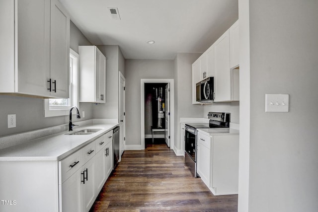 kitchen with dark wood-type flooring, stainless steel appliances, sink, and white cabinets