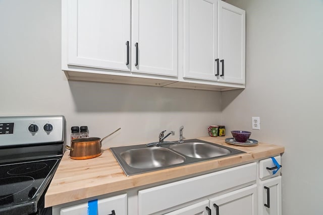 kitchen featuring electric stove, white cabinetry, wooden counters, and sink