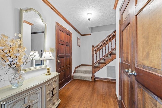 foyer with ornamental molding, dark hardwood / wood-style floors, and a textured ceiling