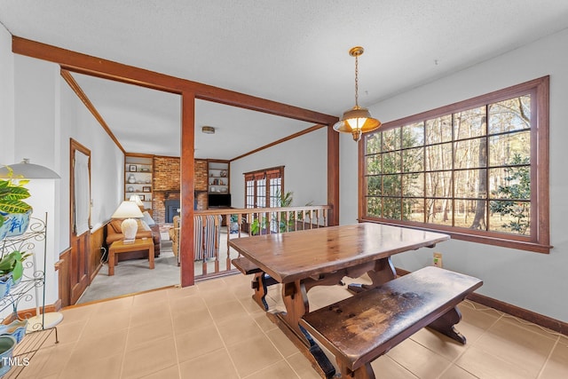 dining space with built in shelves, a brick fireplace, a textured ceiling, and crown molding