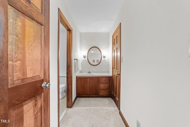 hallway with light carpet, sink, and a textured ceiling