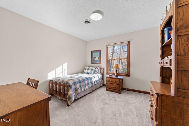 bedroom with light colored carpet and a textured ceiling